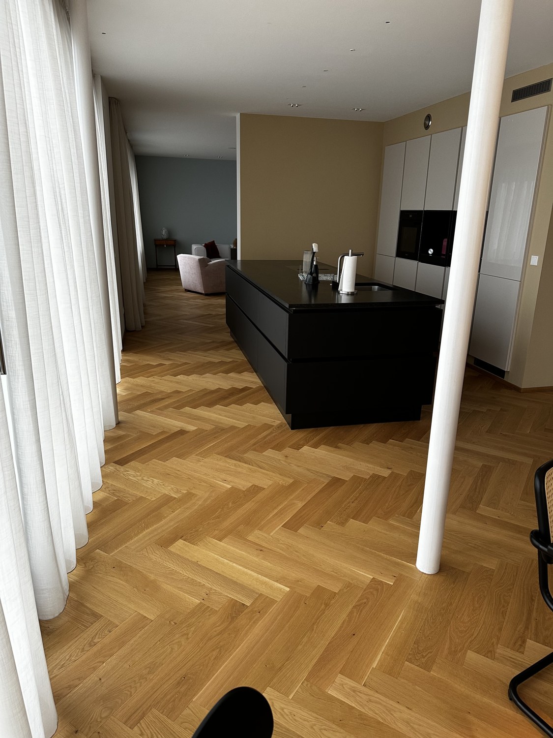 Blick in die Küche mit dunkler Kochinsel.
